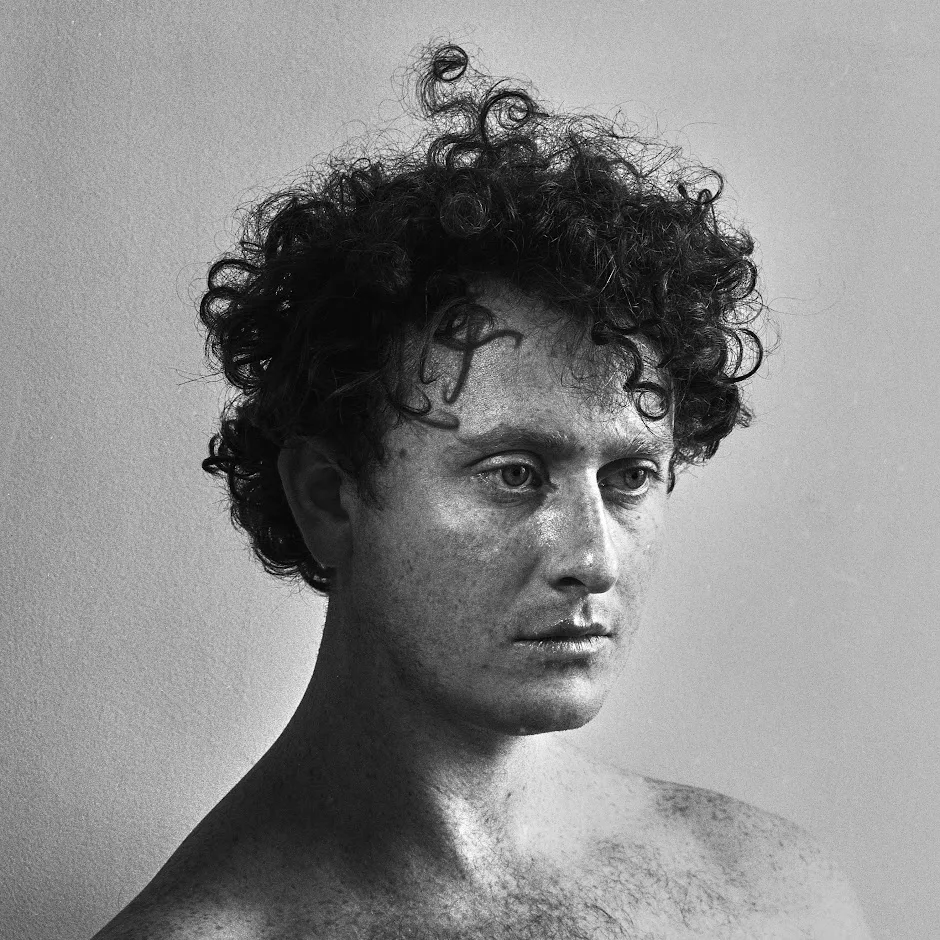 Black and white portrait of Ethan Orchard, with curly dark hair, looking off to the side